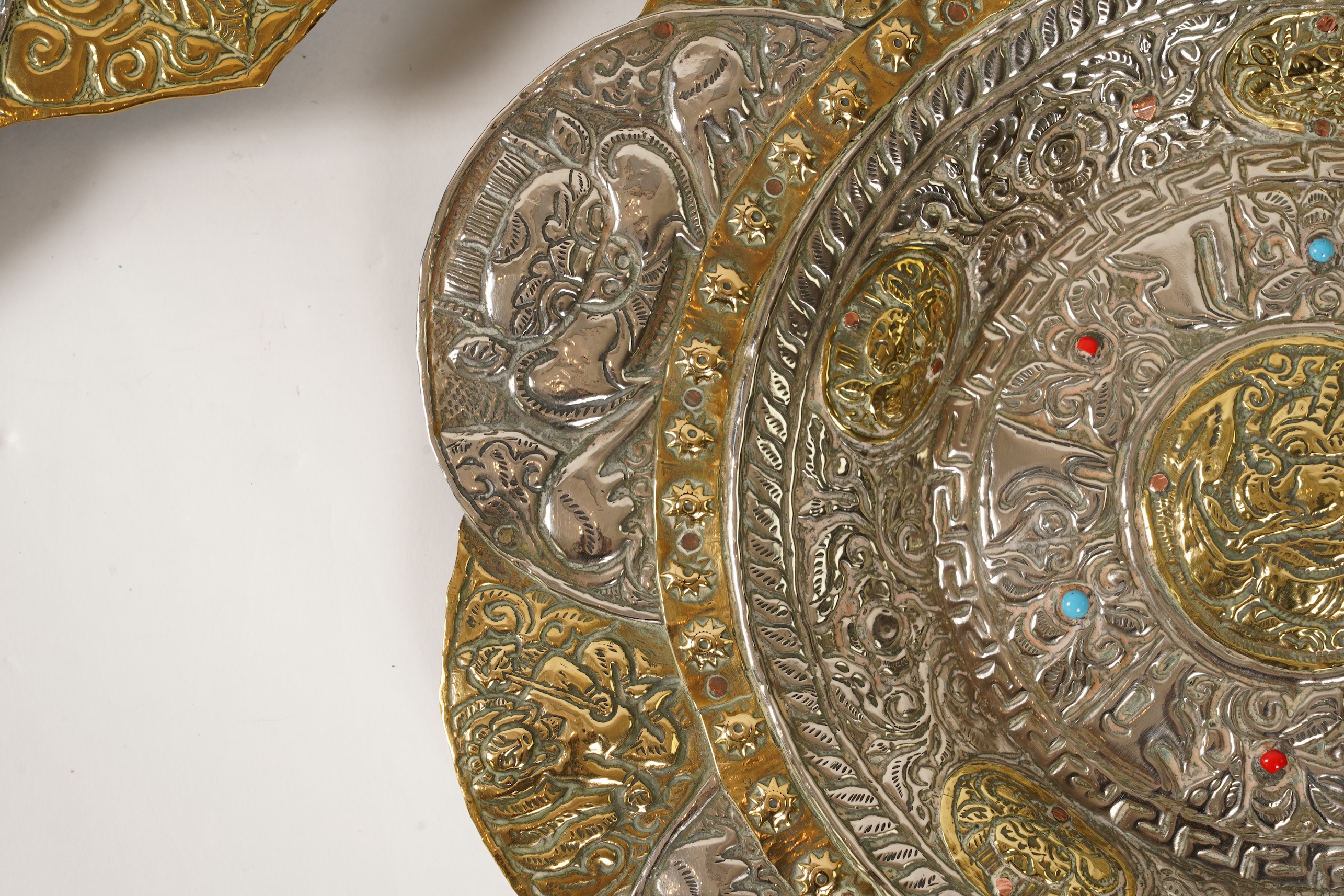 A graduated set of three Nepalese repoussé white metal and brass chargers, first half 20th century